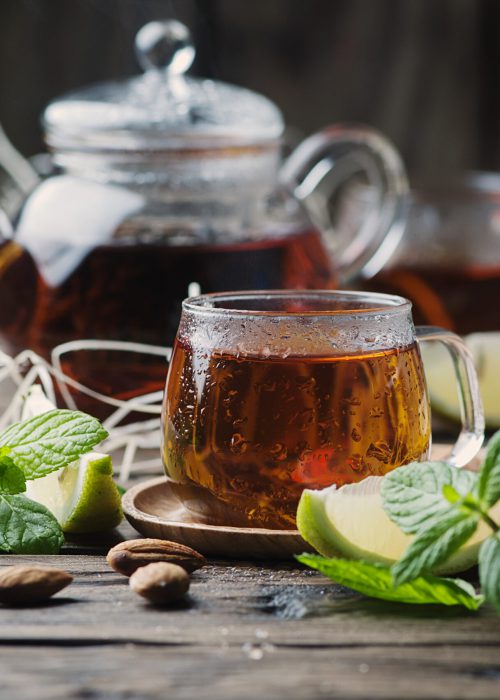 Hot black tea with lemon and mint on the wooden table, selective focus